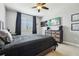 Stylish bedroom featuring a ceiling fan, with a large window and dark curtains, matching dark furniture, and light carpet at 17226 Hickory Wind Dr, Clermont, FL 34711