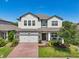 Charming two-story home featuring a brick driveway, manicured lawn and a welcoming front porch at 17226 Hickory Wind Dr, Clermont, FL 34711