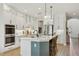 Bright kitchen featuring white cabinets, stainless steel appliances, an island, and modern pendant lighting at 17226 Hickory Wind Dr, Clermont, FL 34711