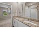 Bathroom featuring a double granite sink vanity with a doorway leading to bedroom with windows at 2304 Mystic Maze Ln, Clermont, FL 34715
