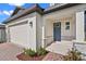 Inviting front entrance of a two-story home with brick accents, covered porch, and a two-car garage at 2304 Mystic Maze Ln, Clermont, FL 34715