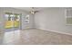 Open living room with tile flooring, sliding glass door access to the backyard, and a ceiling fan at 2304 Mystic Maze Ln, Clermont, FL 34715
