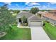 An elevated view of a well-kept home showing the 2-car garage, driveway, and tree-shaded lawn at 27401 Pine Straw Rd, Leesburg, FL 34748
