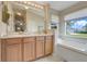 Bright bathroom featuring double sinks, wooden cabinets, soaking tub and natural light from the window at 27401 Pine Straw Rd, Leesburg, FL 34748