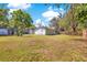 Large backyard with grass, trees, fencing, and detached structures at 2927 Ahern Dr, Orlando, FL 32817