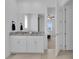 Bright bathroom featuring granite countertops, neutral tile, and a doorway to the primary bedroom at 3017 Ambersweet Pl, Clermont, FL 34711