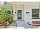Close up of the home's white brick facade, dark front door, and well-kept landscaping at 318 E Jersey St, Orlando, FL 32806