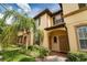 Inviting tan two-story townhome featuring manicured landscaping and a lush palm tree at 3643 Calabria Avenue, Davenport, FL 33897