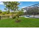Landscaped backyard with a screened pool overlooking the pond with mature trees for privacy and nature at 4751 Aguila Pl, Orlando, FL 32826