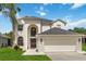 Inviting two-story home featuring an arched entryway, attached two-car garage, and a well-manicured lawn with a palm tree at 4751 Aguila Pl, Orlando, FL 32826