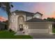 Inviting two-story home featuring an arched entryway, attached two-car garage, and a well-manicured lawn with a palm tree at 4751 Aguila Pl, Orlando, FL 32826