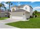 Inviting two-story home featuring an arched entryway, attached two-car garage, and a well-manicured lawn with a palm tree at 4751 Aguila Pl, Orlando, FL 32826