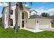 Inviting two-story home featuring an arched entryway, attached two-car garage, and a well-manicured lawn with a palm tree at 4751 Aguila Pl, Orlando, FL 32826