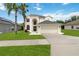 Inviting two-story home featuring an arched entryway, attached two-car garage, and a well-manicured lawn with a palm tree at 4751 Aguila Pl, Orlando, FL 32826