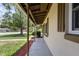 Spacious covered front porch with beige brick exterior, dark wooden shutters, and a concrete floor at 891 N Wayman St, Longwood, FL 32750