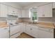 Functional kitchen with white cabinets and appliances, light countertops and tile flooring at 891 N Wayman St, Longwood, FL 32750
