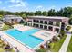 Aerial view of community pool and building with palm trees and landscaping at 917 Royal Oak Blvd, Leesburg, FL 34748