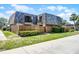 View of townhome featuring a wood fence, lush landscaping, and architectural roof design at 917 Royal Oak Blvd, Leesburg, FL 34748