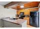 Kitchen featuring a breakfast bar, black appliances, and wood cabinets at 917 Royal Oak Blvd, Leesburg, FL 34748