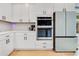 Close up of kitchen featuring built in oven and modern refrigerator with white cabinets and shelving at 1127 W Harvard St, Orlando, FL 32804