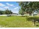 Expansive backyard with green grass and mature trees under cloudy skies at 114 Floral Dr, Kissimmee, FL 34743