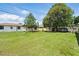 Wide open backyard with green grass and mature trees under cloudy skies at 114 Floral Dr, Kissimmee, FL 34743