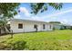 Large green lawn features white house and cloudy blue skies at 114 Floral Dr, Kissimmee, FL 34743
