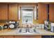 Kitchen area with stainless steel sink, wood cabinets, and a window view at 114 Floral Dr, Kissimmee, FL 34743