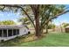 Lush green backyard with manicured lawn, mature trees, and the rear of the house with attached screen porch at 1204 Howell Creek Dr, Winter Springs, FL 32708