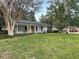 Charming home with a bright yellow door, a beautiful lawn and mature landscaping at 1204 Howell Creek Dr, Winter Springs, FL 32708