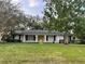 Charming single story home featuring a bright yellow front door, large yard, and mature trees at 1204 Howell Creek Dr, Winter Springs, FL 32708