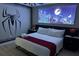 This bedroom features a queen-size bed, ceiling fan, and a custom mural that adds a playful and unique ambiance at 1466 Moon Valley Dr, Champions Gate, FL 33896