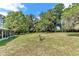 Expansive backyard view featuring lush green grass, mature trees and partial view of the screened-in lanai at 2299 Nw 135Th Ln, Citra, FL 32113