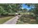 Long, paved driveway leading to a charming home surrounded by mature trees and a wooden fence at 2299 Nw 135Th Ln, Citra, FL 32113