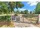 Metal gate adorned with 'Galloping Goats Ranch' and bat decorations, leading to a home at 2299 Nw 135Th Ln, Citra, FL 32113