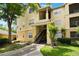Inviting yellow condo building featuring well-kept landscaping, a stairway, and balcony, all set against a blue sky and green trees at 2652 Robert Trend Jones # 2652, Orlando, FL 32835