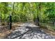 Long paved driveway leading through a wooded area, secured by a black iron gate at 2705 Curryville Rd, Chuluota, FL 32766
