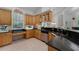 Well-lit kitchen with wooden cabinets, dark countertops, stainless steel dishwasher, and a view to the outside at 2705 Curryville Rd, Chuluota, FL 32766