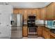 Kitchen with stainless steel appliances, including a refrigerator, oven, microwave, and wooden cabinets and dark countertops at 2705 Curryville Rd, Chuluota, FL 32766