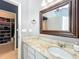 Bathroom vanity with granite countertop, framed mirror, and a view of the walk-in closet at 2706 Donaldson Dr, Orlando, FL 32812
