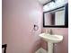 Small bathroom with a pedestal sink, decorative mirror, and updated fixtures at 2706 Donaldson Dr, Orlando, FL 32812