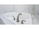 Close-up of luxurious white bathtub with stylish faucet and marbled tile surround at 278 Acorn Dr, Longwood, FL 32750