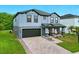 A gray two-story home featuring a brick-paved driveway and well-maintained landscaping at 2926 Boating Blvd, Kissimmee, FL 34746