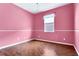 A pink bedroom offers bright natural light and hardwood floors at 2975 White Cedar Cir, Kissimmee, FL 34741