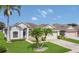 Inviting one-story home with tropical landscaping, a well-maintained lawn, and an attached garage at 2975 White Cedar Cir, Kissimmee, FL 34741