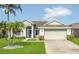 Charming single-story home featuring lush landscaping, a two-car garage, and a welcoming entryway at 2975 White Cedar Cir, Kissimmee, FL 34741