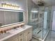 Bathroom featuring an illuminated mirror, double vanity and glass enclosed shower with gold hardware at 3146 Byington Terrace Ter, Deltona, FL 32738