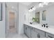 This bathroom boasts double sinks with modern black hardware and a large mirror with decorative lighting at 3361 Orange Rose Loop, Apopka, FL 32712