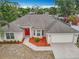 Aerial view of a charming single-story home with a red front door, lush landscaping, and an attached two-car garage at 404 Wilshire Dr, Casselberry, FL 32707
