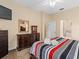Comfortable bedroom with red, white, and gray striped bedding, dresser, and a television for relaxing evenings at 426 Vista Loop, Davenport, FL 33897